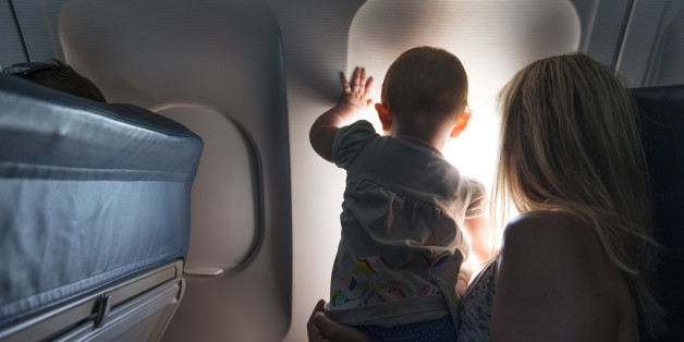 Baby looking out airplane window. 