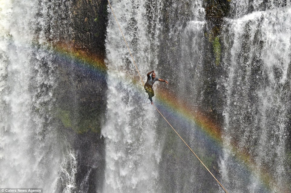 As Reginaldo weaved and balanced on the rope, a beautiful rainbow looped over and brilliantly framed the photographs. Image by Caters News Agency