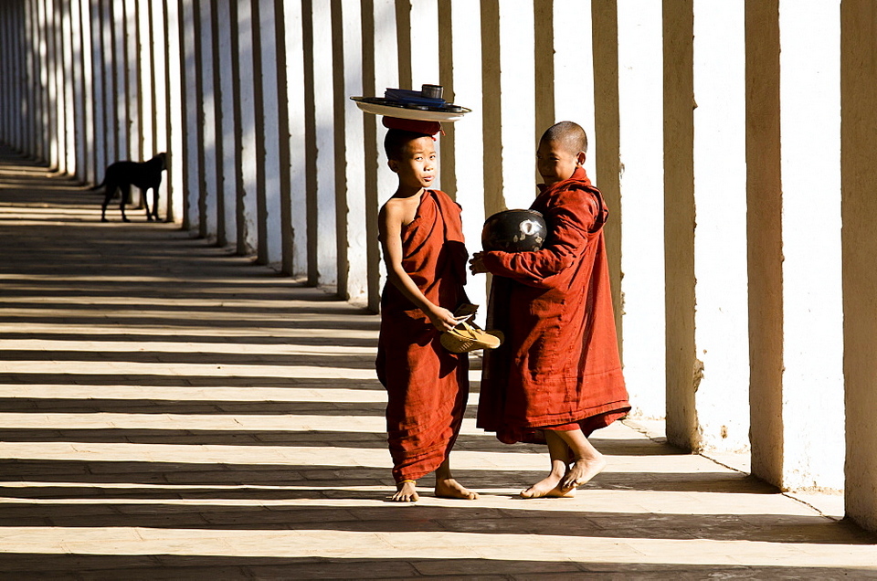 Novice Buddhist monks collecting alms, standing in the shadows of columns at Shwezigon Paya. Picture: shwezigon temple blog.