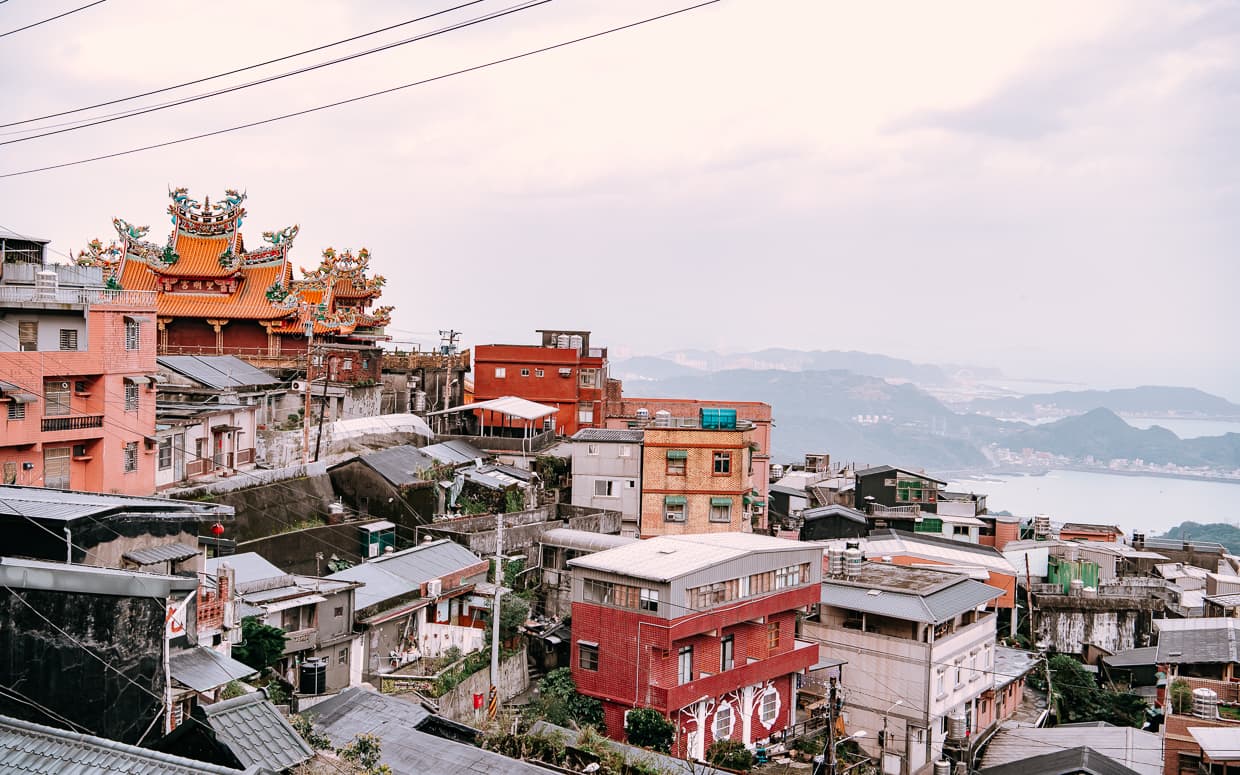 The mountainside village of Jiufen with a temple and the ocean.