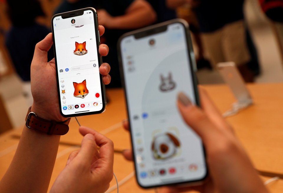 People try out the Animoji feature on iPhone X handsets during its launch at the Apple store in Singapore