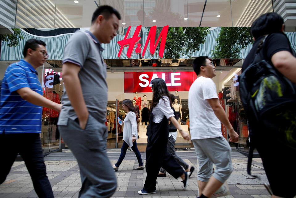 People walk past a H&M fashion chain store at Tsim Sha Tsui shopping district in Hong